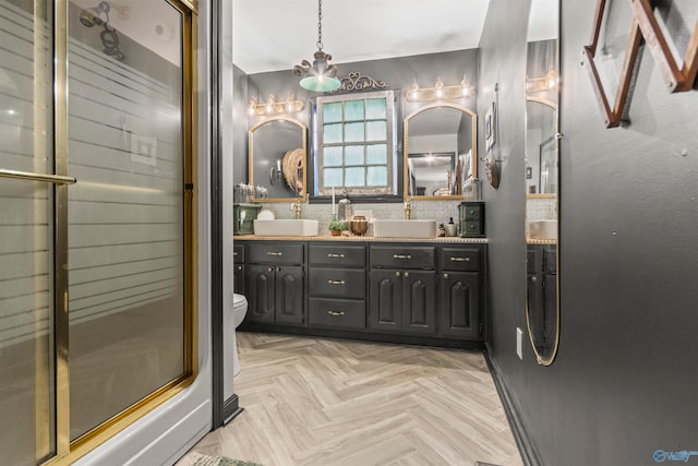 bathroom featuring parquet floors, an inviting chandelier, a shower with shower door, vanity, and toilet