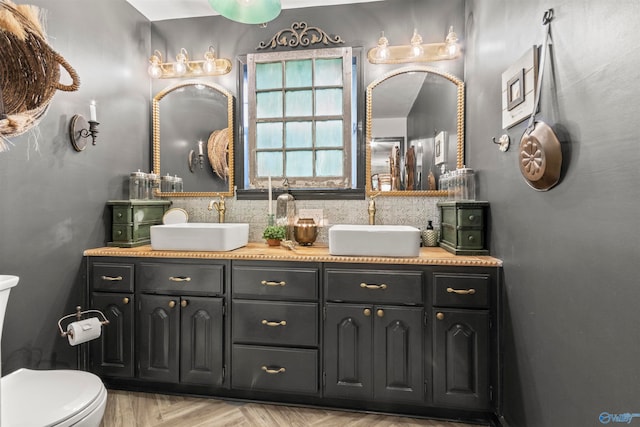 bathroom with tasteful backsplash, parquet floors, vanity, and toilet