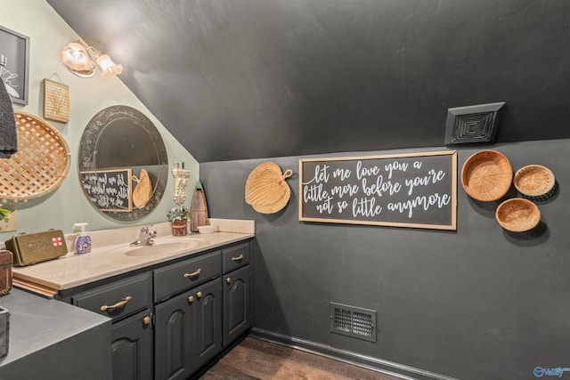 bathroom with hardwood / wood-style floors, vanity, and vaulted ceiling