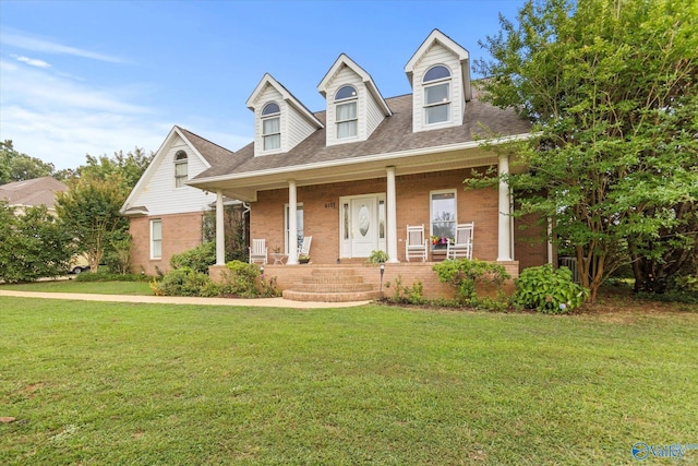 new england style home featuring covered porch and a front lawn