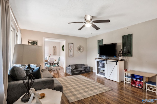 living room featuring dark wood-type flooring and ceiling fan