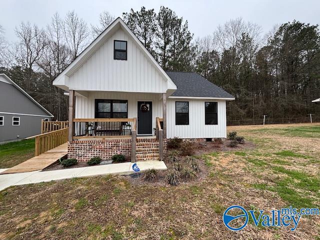 modern farmhouse style home with covered porch, roof with shingles, crawl space, a front lawn, and board and batten siding