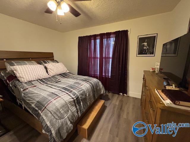 bedroom featuring a textured ceiling, dark wood-style flooring, a ceiling fan, and baseboards