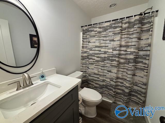 full bathroom with toilet, a textured ceiling, vanity, wood finished floors, and a shower with curtain