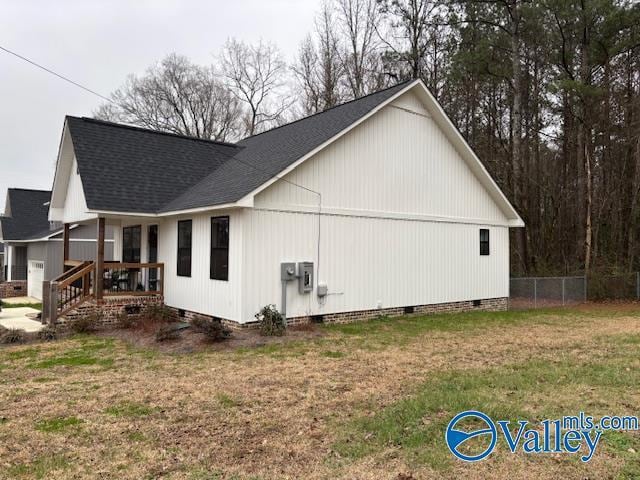 view of property exterior with roof with shingles, crawl space, fence, and a lawn