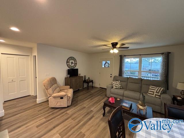 living room with ceiling fan, baseboards, and wood finished floors