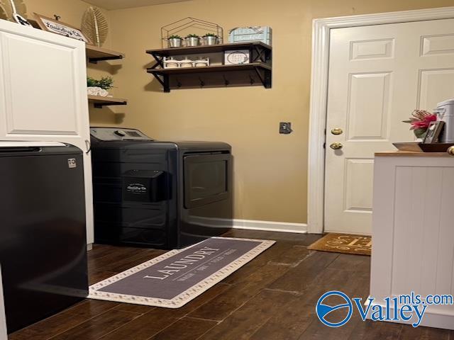 washroom featuring dark wood finished floors, laundry area, baseboards, and washer and clothes dryer