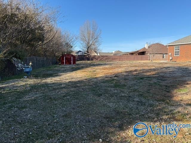 view of yard featuring an outdoor structure, a storage unit, and fence