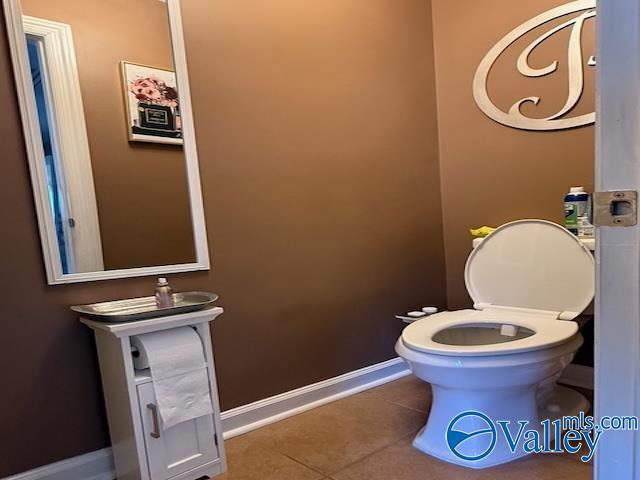 bathroom with tile patterned floors, baseboards, and toilet