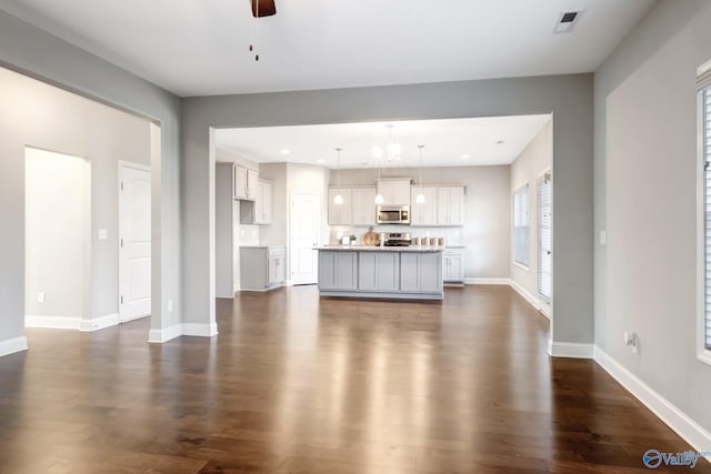 unfurnished living room featuring ceiling fan and dark wood-type flooring