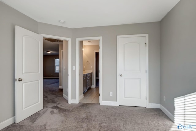 unfurnished bedroom featuring light colored carpet and ensuite bathroom