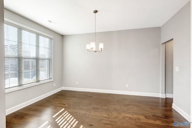 spare room featuring a chandelier and dark hardwood / wood-style floors