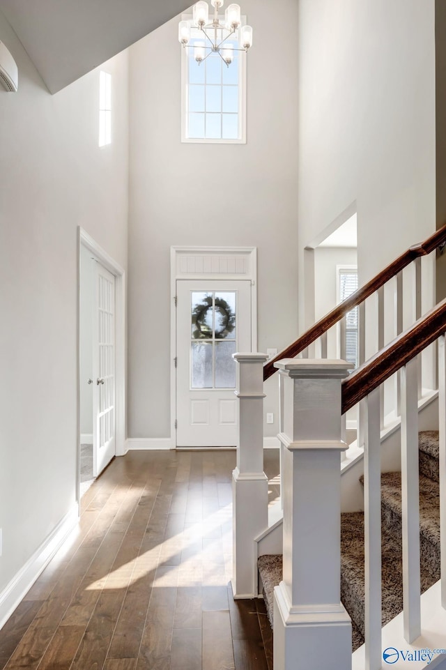 entrance foyer featuring a wall unit AC, a towering ceiling, and a chandelier