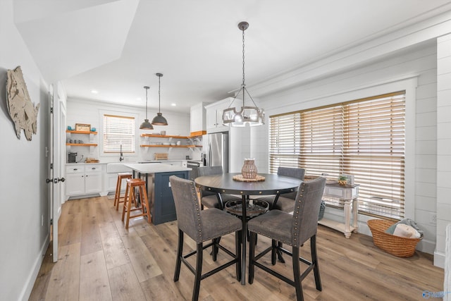 dining room with light wood-type flooring, an inviting chandelier, and a wealth of natural light