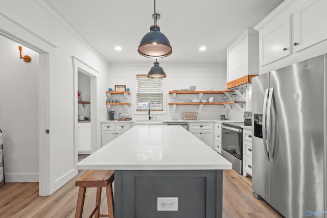 kitchen with sink, stainless steel appliances, light hardwood / wood-style flooring, pendant lighting, and white cabinets