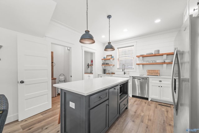 kitchen featuring white cabinets, light hardwood / wood-style floors, hanging light fixtures, and appliances with stainless steel finishes