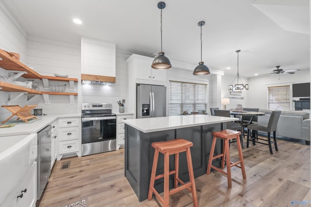 kitchen featuring white cabinetry, a center island, stainless steel appliances, and light wood-type flooring