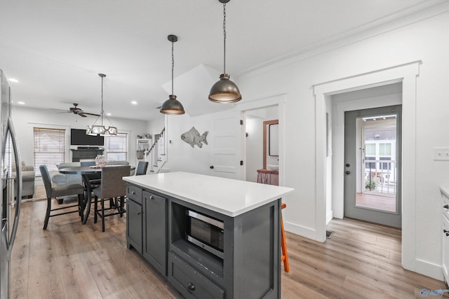 kitchen with pendant lighting, light wood-type flooring, a center island, and ceiling fan