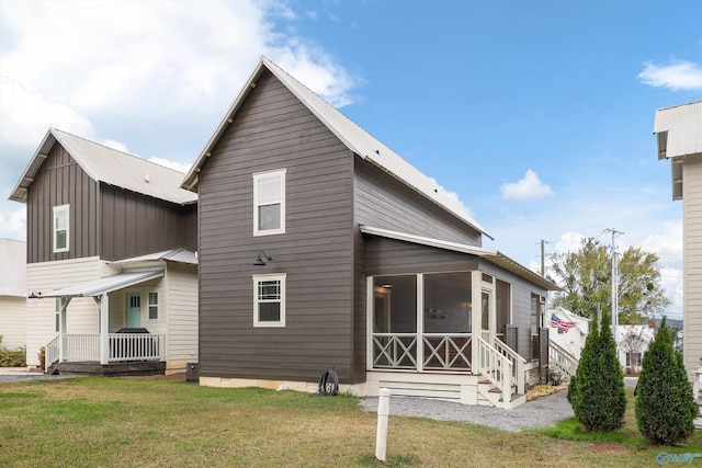 rear view of house featuring a sunroom and a yard