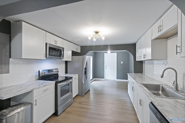929 Carroll Rd, Harvest, AL 35759 - kitchen featuring stainless steel appliances, a sink, white cabinets, light wood-type flooring, and arched walkways