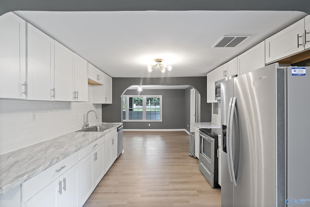 929 Carroll Rd, Harvest, AL 35759 - kitchen featuring appliances with stainless steel finishes, a sink, arched walkways, tasteful backsplash, and white cabinetry