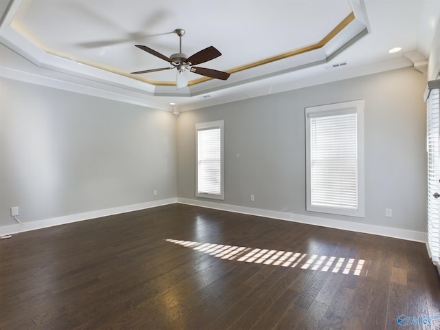 empty room featuring ceiling fan, a raised ceiling, ornamental molding, and dark wood-type flooring