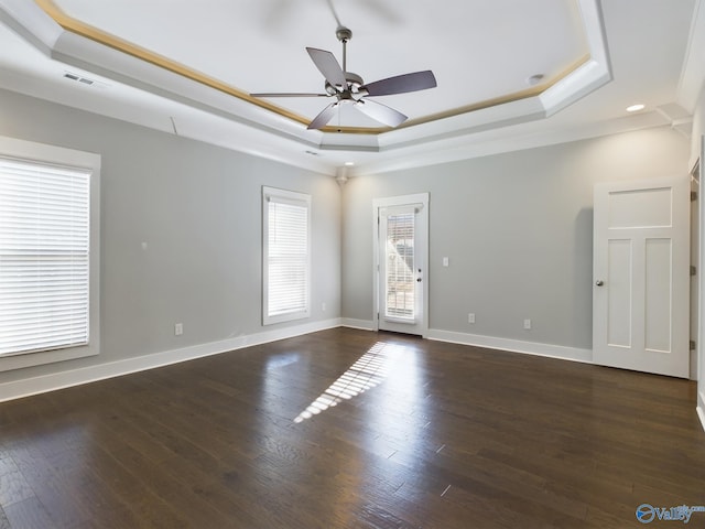 empty room with dark hardwood / wood-style floors, ceiling fan, and a raised ceiling