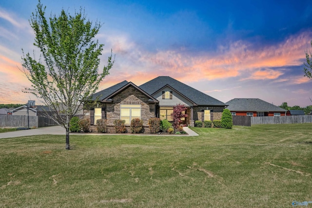 view of front of property with a front lawn, fence, and stone siding