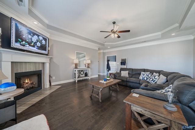 living area featuring baseboards, ceiling fan, hardwood / wood-style flooring, a fireplace, and a raised ceiling