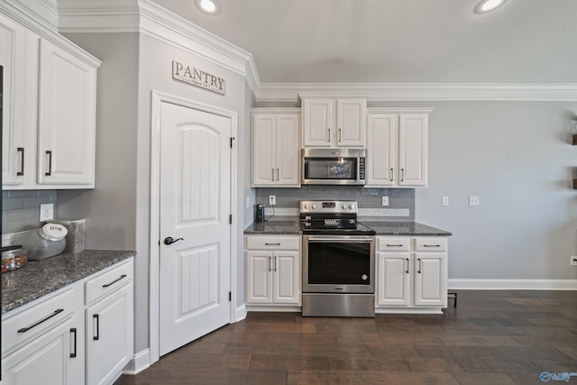 kitchen with white cabinets, dark stone counters, backsplash, and appliances with stainless steel finishes
