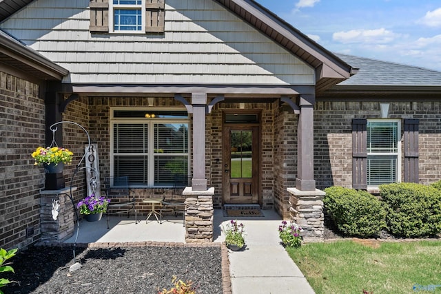 property entrance with a porch and brick siding