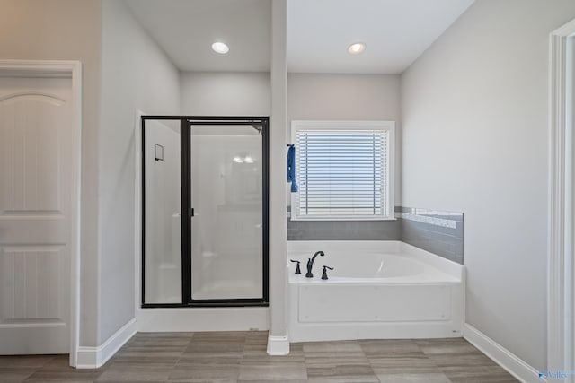 bathroom with a bath, baseboards, and a stall shower