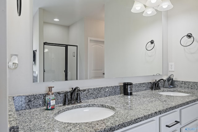 full bathroom with double vanity, a stall shower, and a sink