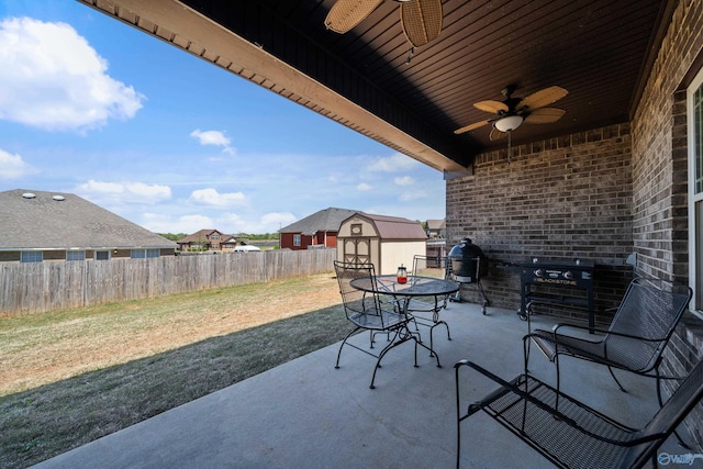 view of patio / terrace featuring a storage shed, a ceiling fan, a fenced backyard, and an outdoor structure