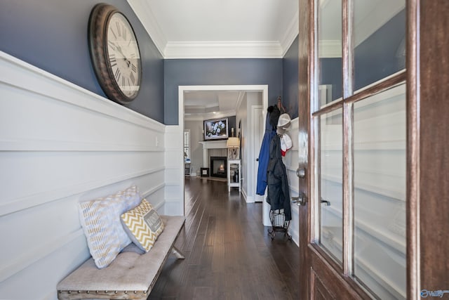 interior space with dark wood-style flooring, crown molding, and a lit fireplace
