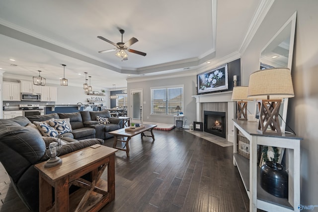 living area with a fireplace with flush hearth, ceiling fan, a raised ceiling, baseboards, and dark wood-style flooring