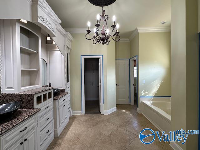 752 12th Way NE, Arab, AL 35016 - bathroom featuring a bath, two vanities, baseboards, an inviting chandelier, and crown molding