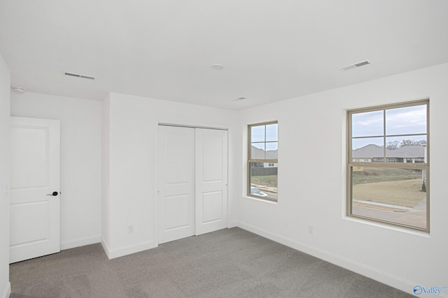 unfurnished bedroom featuring multiple windows, carpet flooring, and a closet