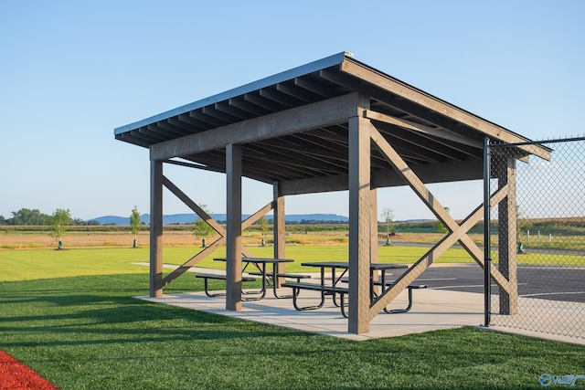 view of community featuring a rural view, a lawn, and a patio