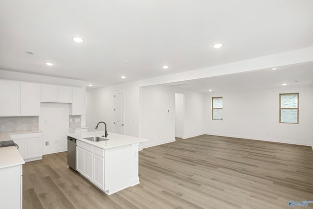 kitchen with dishwasher, sink, white cabinets, a kitchen island with sink, and light hardwood / wood-style flooring