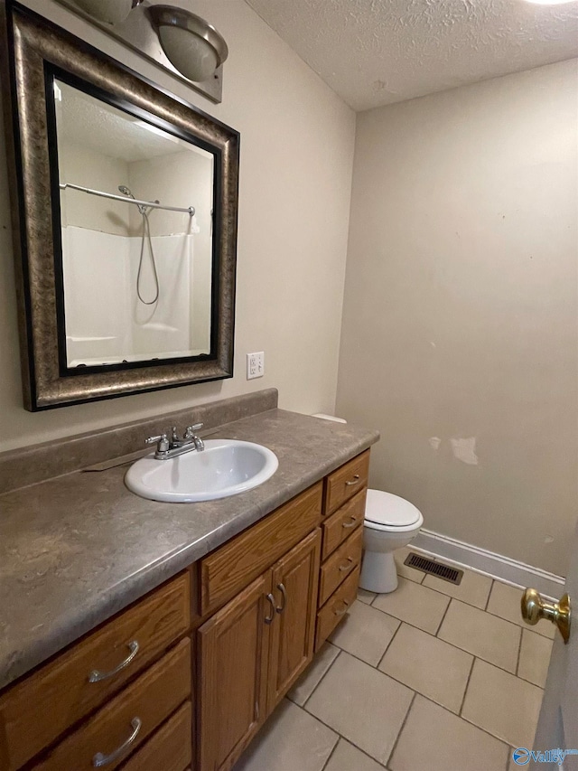 bathroom featuring toilet, tile patterned floors, a textured ceiling, vanity, and walk in shower