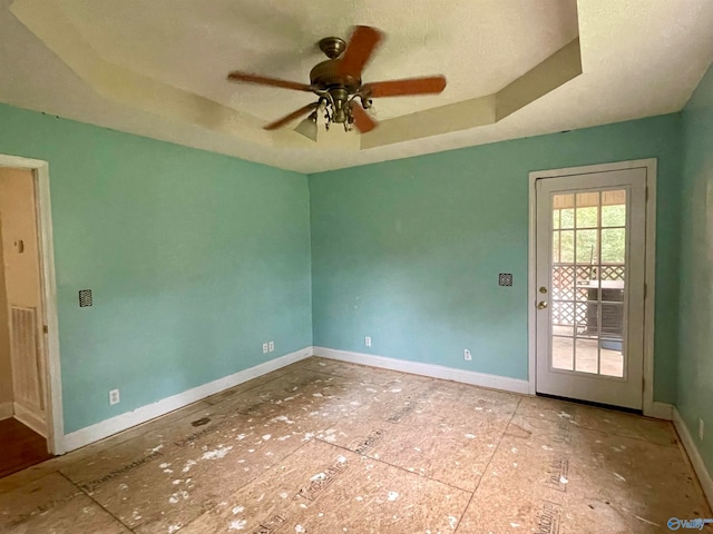 unfurnished room with ceiling fan, a textured ceiling, and a tray ceiling