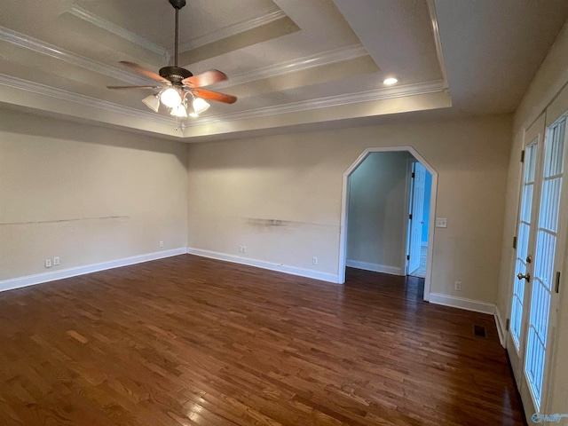 empty room featuring dark wood-type flooring, ceiling fan, a raised ceiling, and crown molding