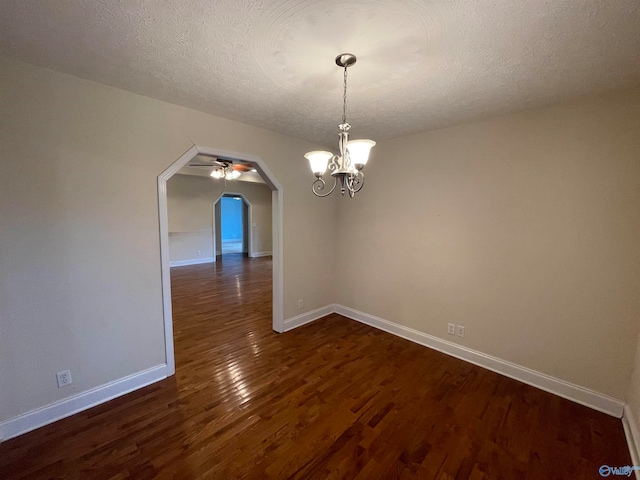 unfurnished dining area featuring dark wood-type flooring, ceiling fan with notable chandelier, and a textured ceiling