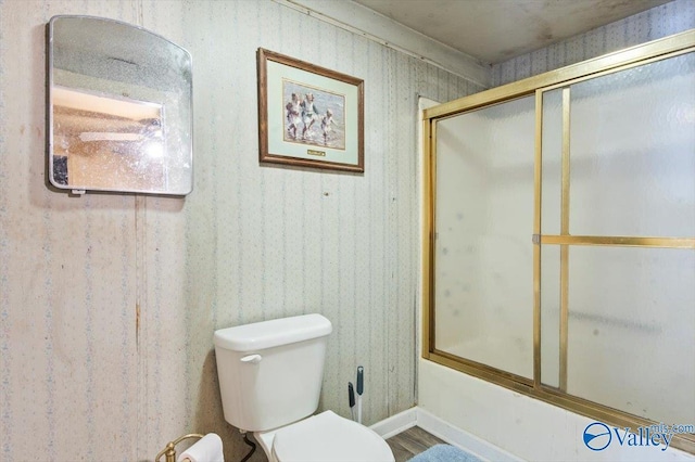 bathroom with combined bath / shower with glass door and toilet