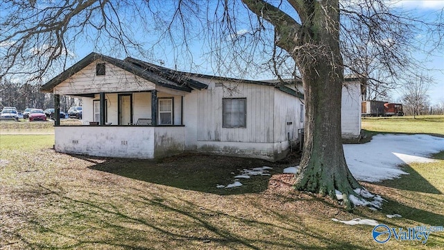 view of side of property with a lawn and covered porch