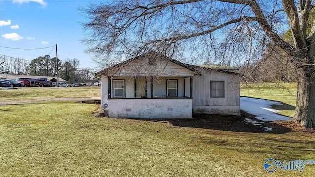 view of side of property featuring covered porch and a lawn