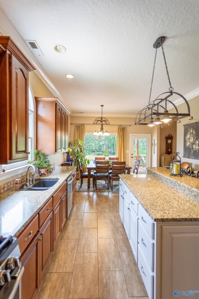 kitchen featuring range, sink, hanging light fixtures, white cabinetry, and dishwasher