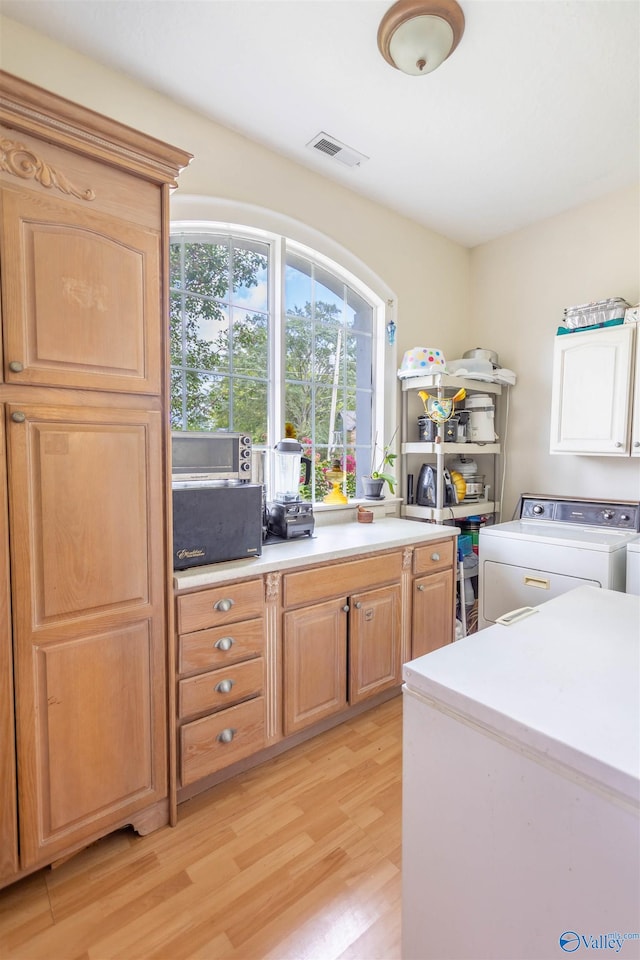 kitchen featuring washing machine and dryer and light hardwood / wood-style floors