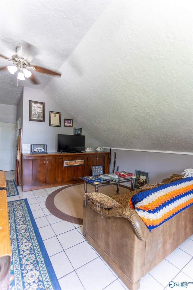 interior space with a textured ceiling, ceiling fan, vaulted ceiling, and light tile patterned floors